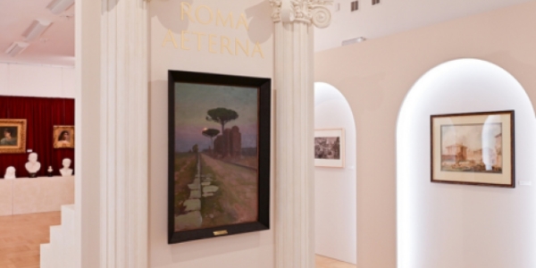 Fotografia wnętrza galerii: kolumny, pastelowe ściany i oprawione obrazy