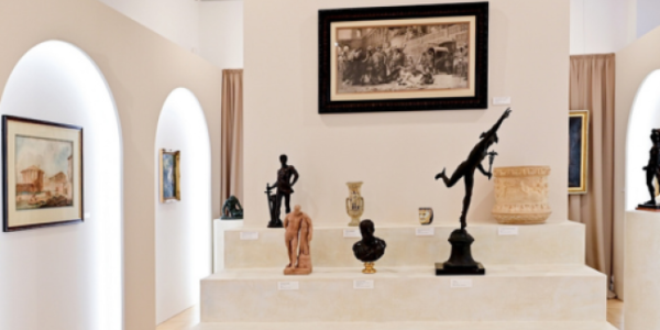 Fotografia wnętrza galerii z białym piedestałem i kilkoma rzeźbami