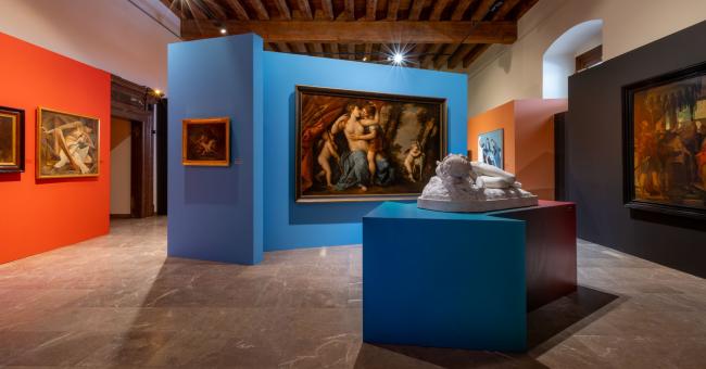 Fotografia wnętrza galerii: niebiesko-pomarańczowe ściany, obrazy i rzeźba