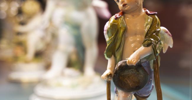 Fotografia porcelanowej figurki chłopca z kapeluszem, zielono-złote akcenty