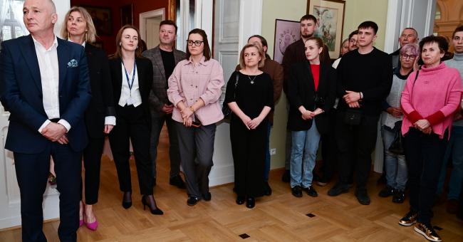 Fotografia grupowa kilkunastu dorosłych w eleganckim salonie