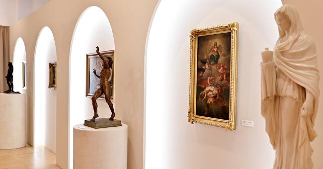 Wnętrze galerii z rzeźbami na piedestałach i obrazem w złotej ramie