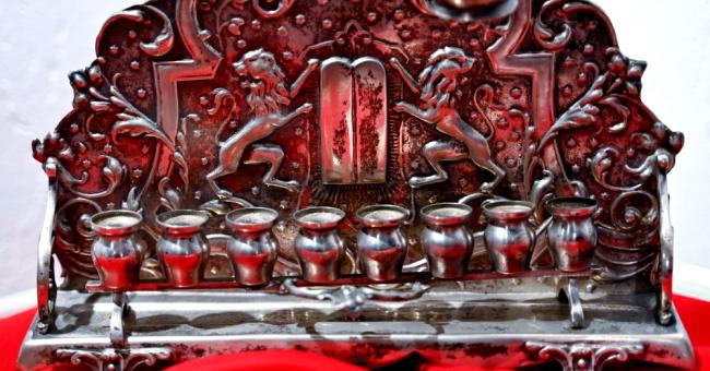 Fotografia ozdobnej antycznej kasy z ciemnego metalu na czerwonym tle