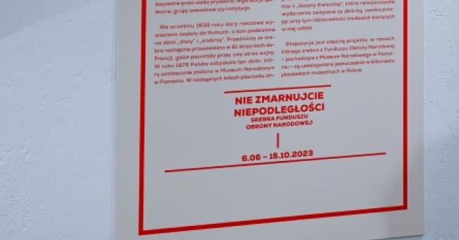 Fotografia białego plakatu z czerwonym nagłówkiem "MOZAIKA KULTUR" i odbiciem na podłodze