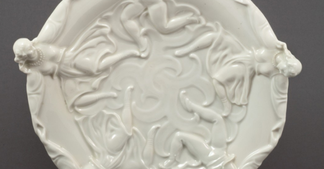 Fotografia białego ceramicznego talerza z reliefowym roślinnym wzorem i trzema uchwytami
