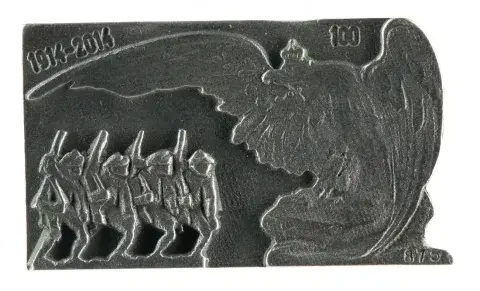 Srebrna metalowa plakieta z reliefem maszerujących żołnierzy i dużego orła