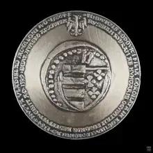 Srebrny medal z herbem w środku i napisem wzdłuż krawędzi