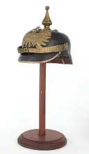 Fotografia hełmu pruskiego pickelhaube z kolcem na drewnianym stojaku