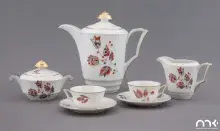 Fotografia białej porcelanowej zastawy herbacianej z czerwono-czarnym wzorem i złotymi detalami
