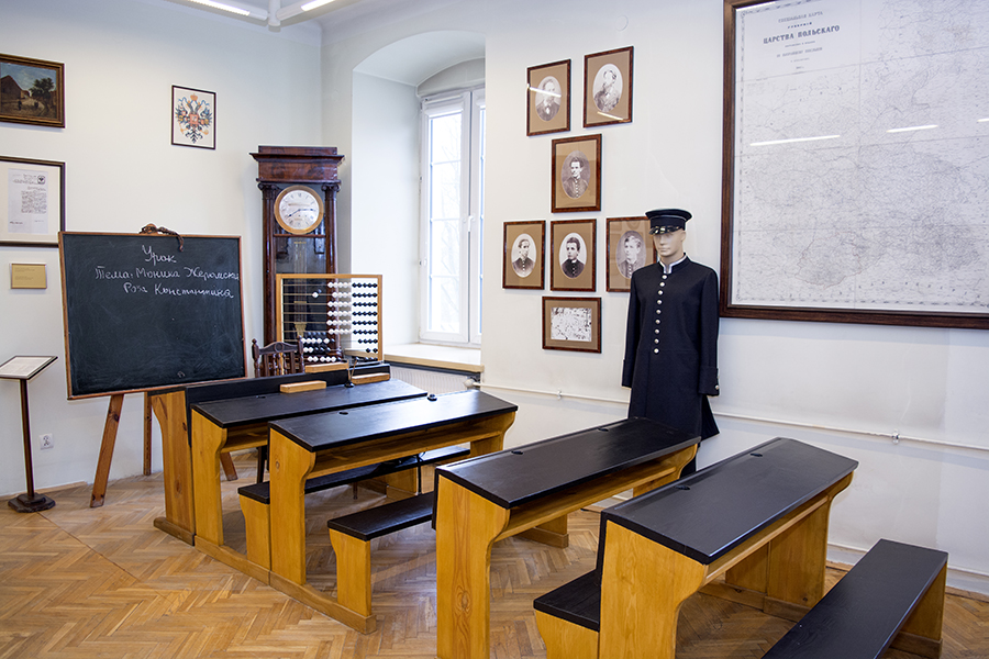 Dawna sala lekcyjna w Muzeum Lat Szkolnych Stefana Żeromskiego, na pierwszym planie ławki, dalej dawny mundurek szkolny